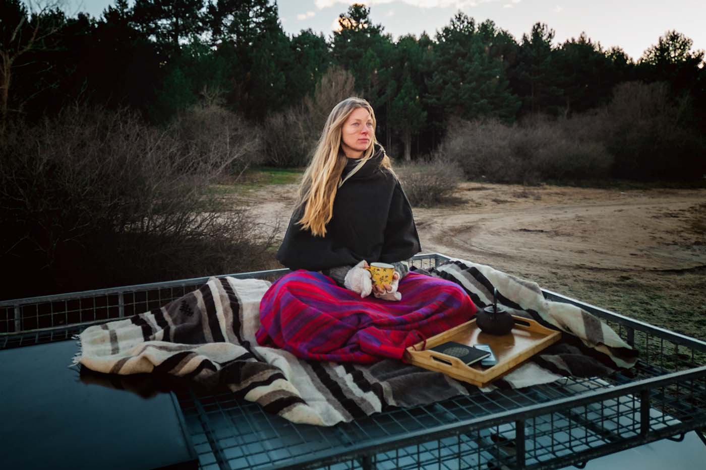 woman sat on campervan roof drinking tea