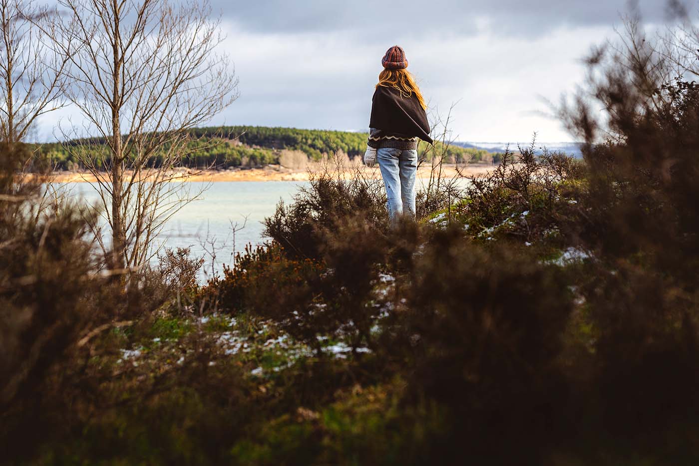 woman exploring the hills of Spain's mountains with pine trees and lake